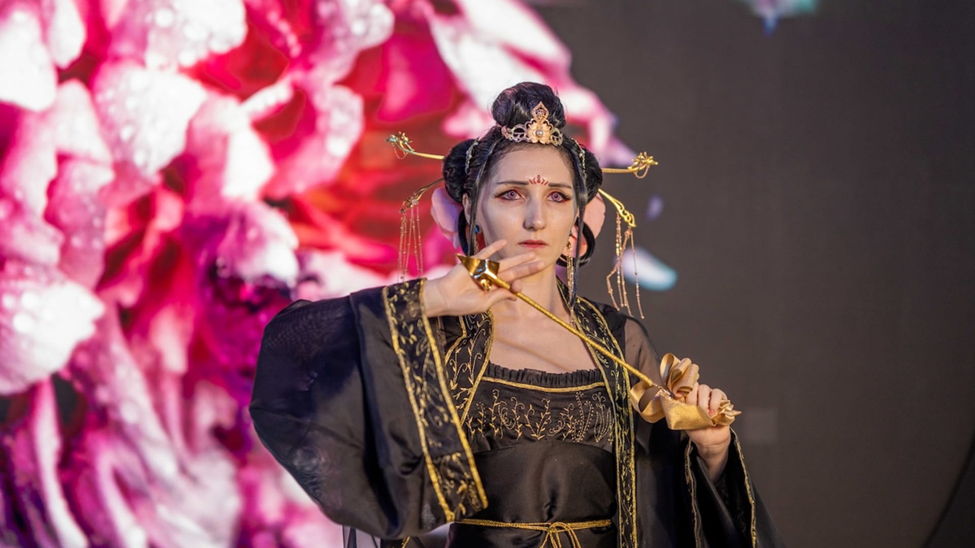 Cosplayers in detailed costumes performing on a stage in front of a judging panel and audience at Aljada.