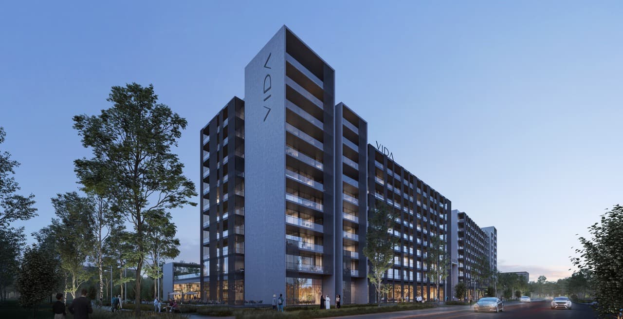 A modern hotel exterior with clean lines and glass facades surrounded by landscaped greenery in a bright urban setting.