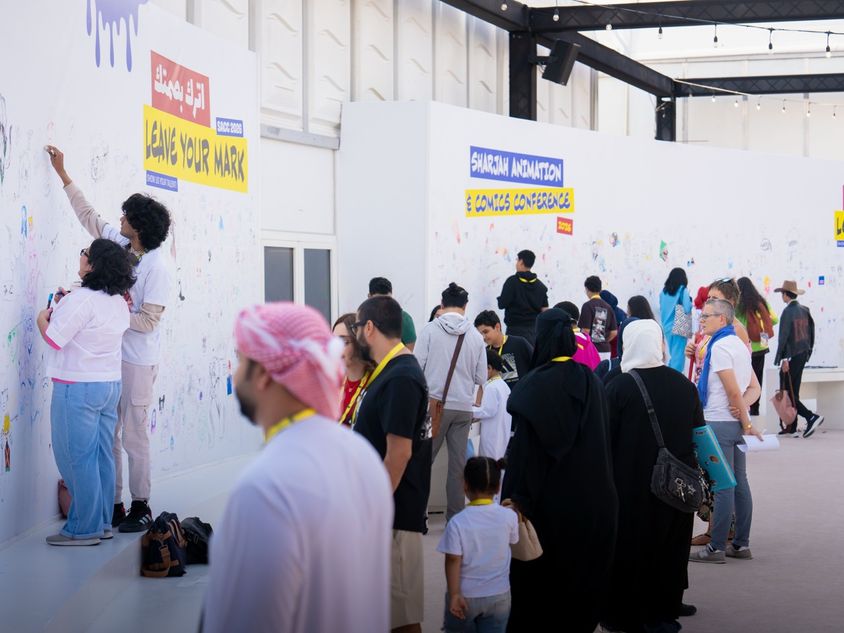 A large crowd of visitors and artists participating in a creative workshop at a modern event space in Aljada.