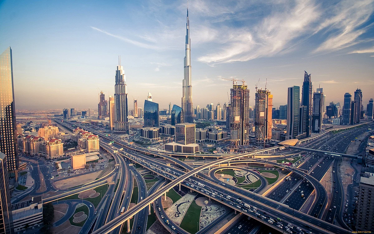 Modern residential apartment buildings and landscaped walkways in a new urban development in Sharjah.