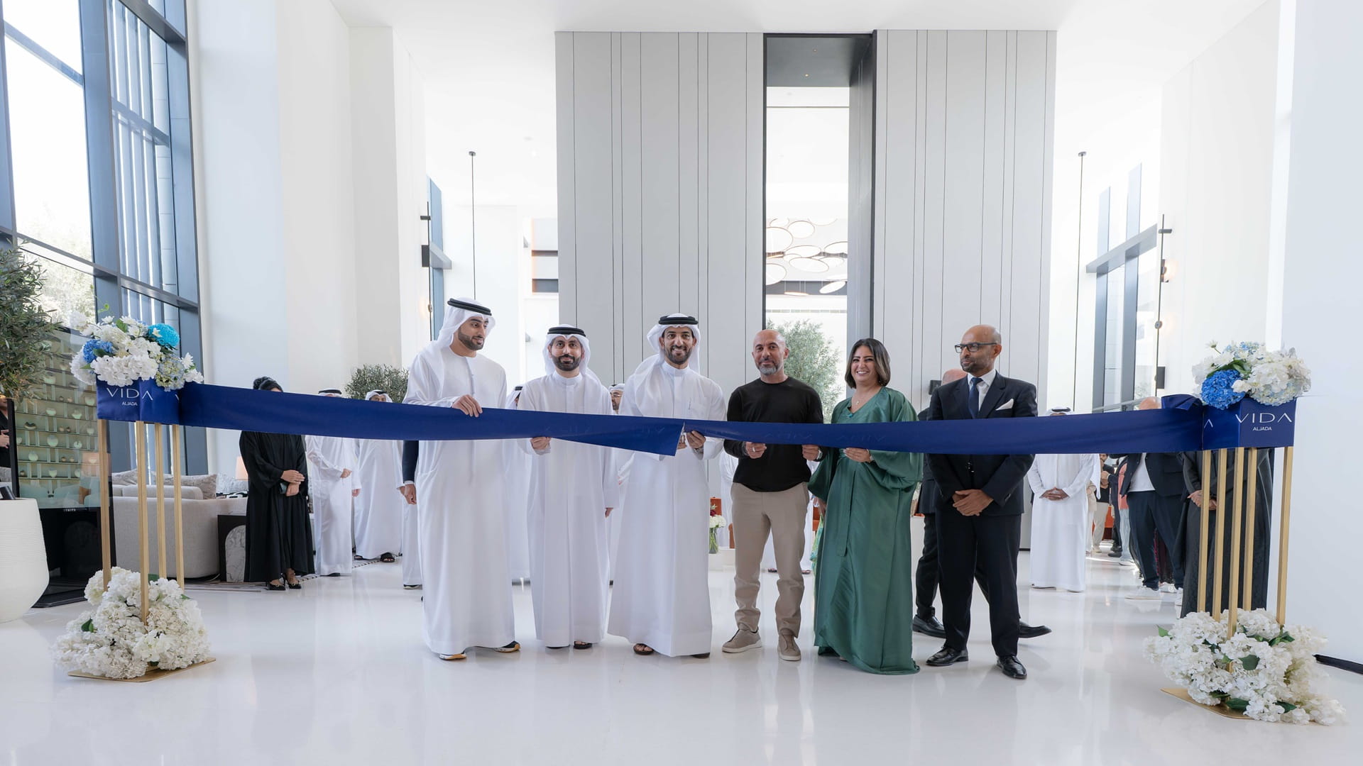 A dignitary cutting a ribbon at the entrance of a modern five-star hotel with contemporary architecture.